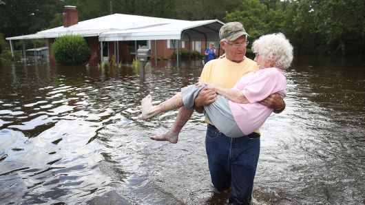 a man holding a woman in the middle of a flooded street