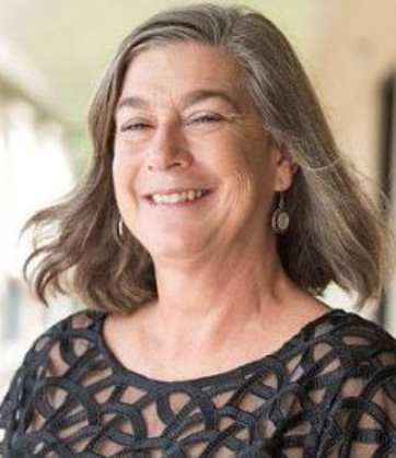 an older woman with grey hair smiling at the camera