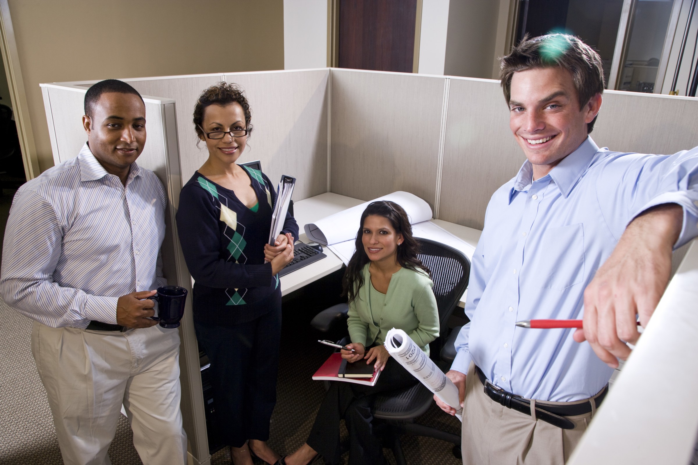 three people standing in an office cubicle holding scissors