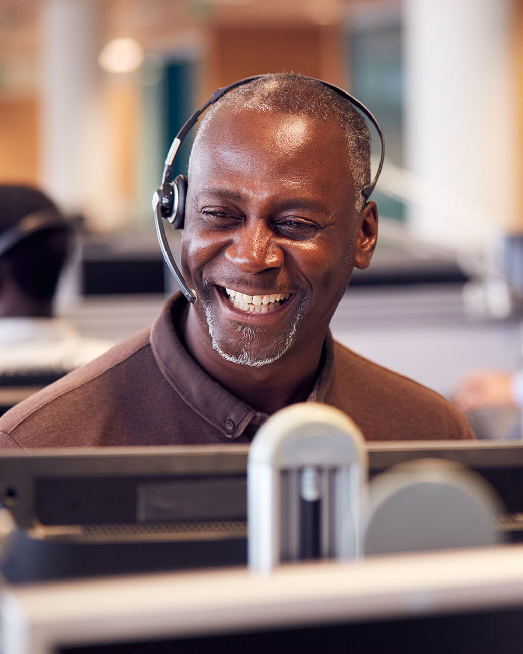 a man wearing a headset smiles as he works on a computer