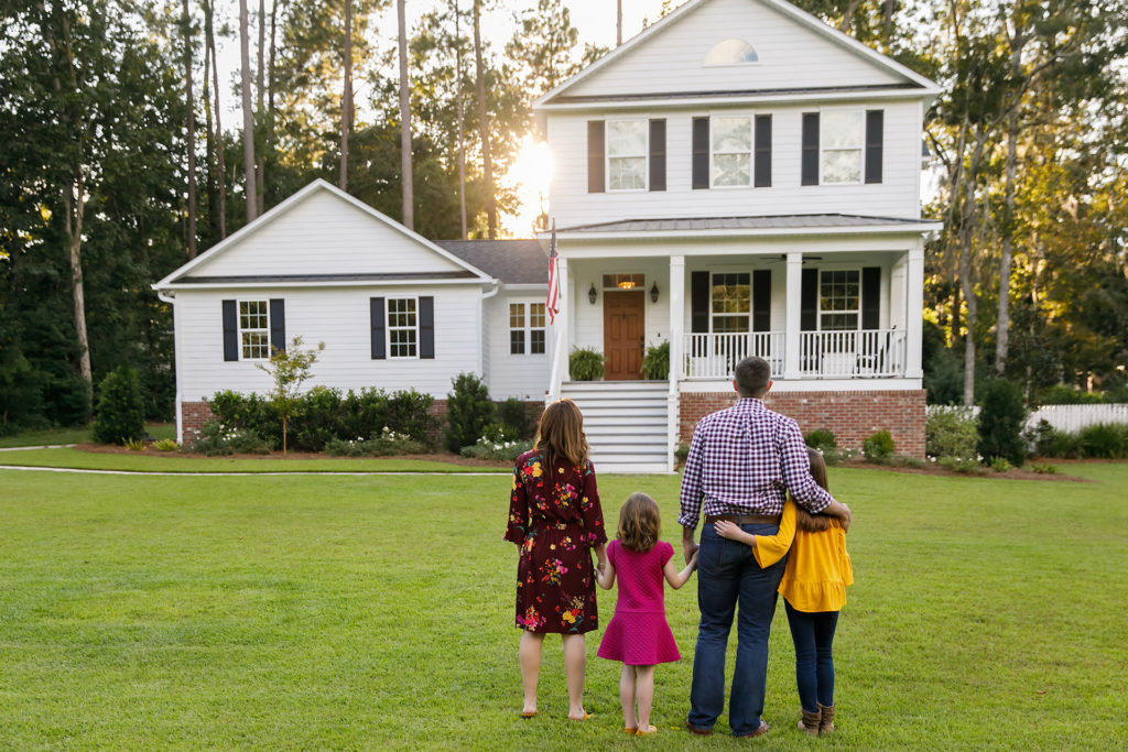 a family walking in front of a white house