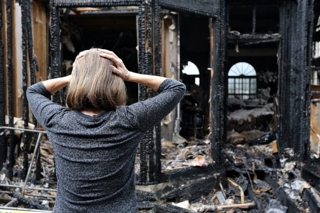 a woman standing in front of a burned building