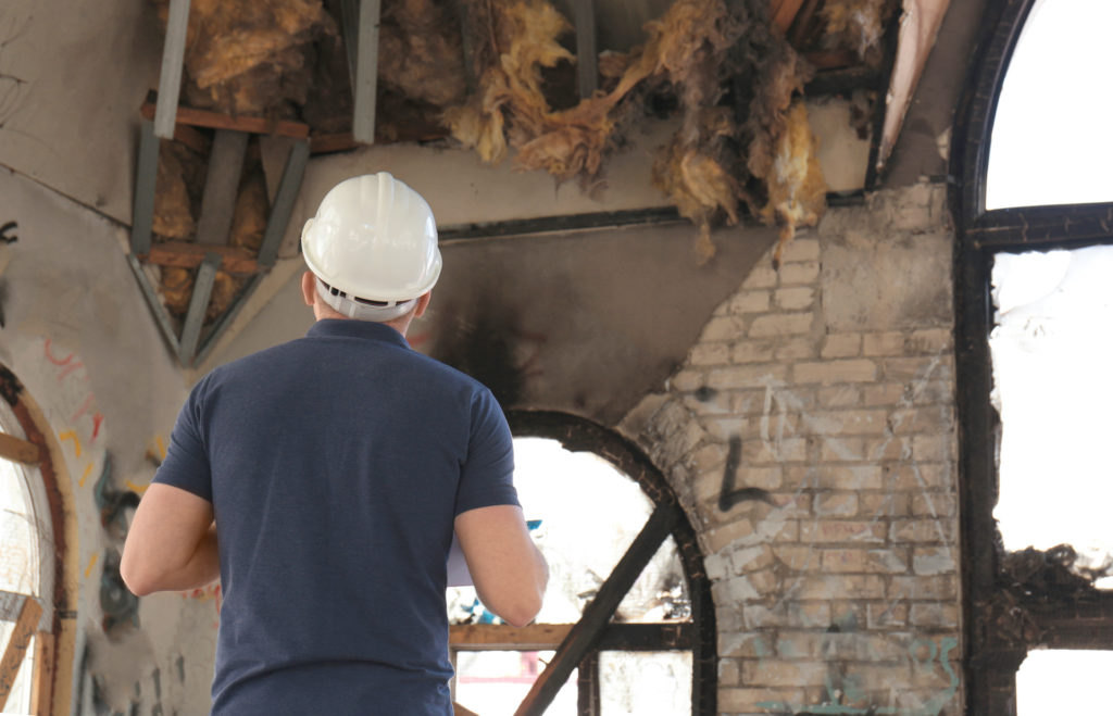 a man wearing a hard hat standing in front of a brick wall