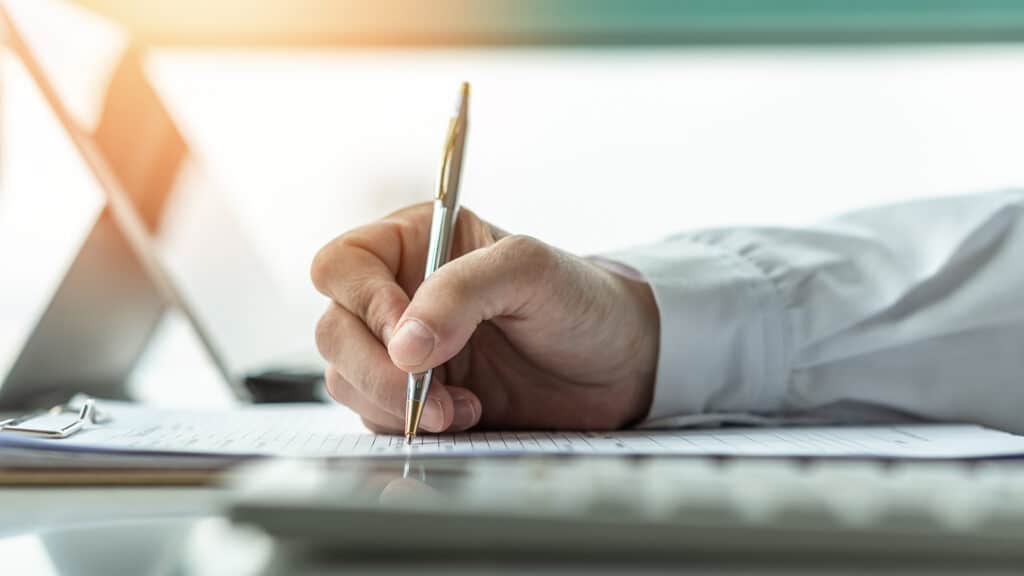 a person writing on a piece of paper with a pen