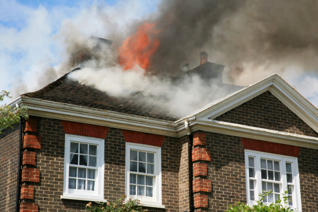 smoke billows from the roof of a brick building