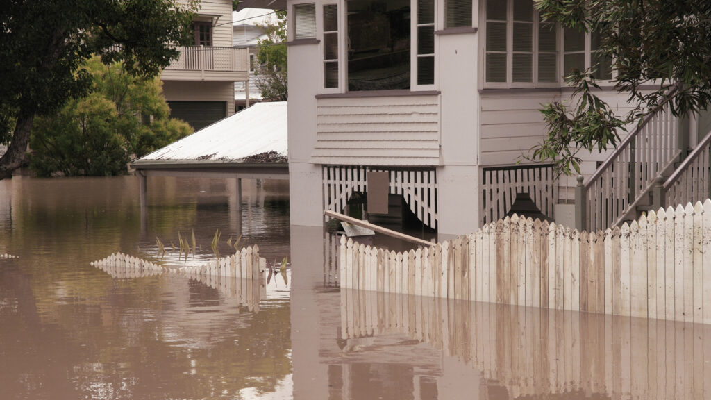 a flooded street with houses and trees in the background