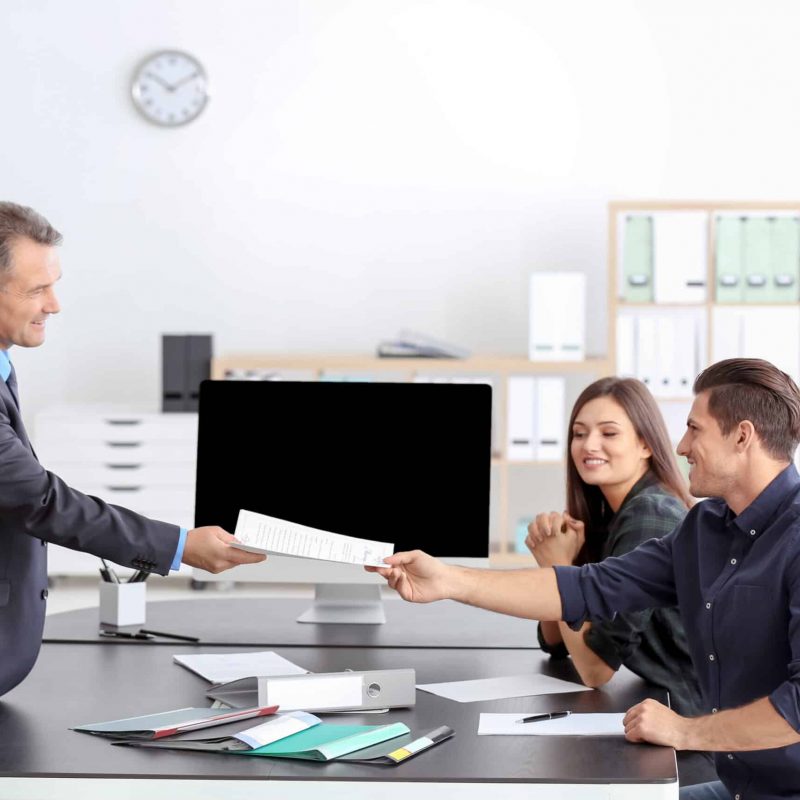 a group of people sitting around a table shaking hands